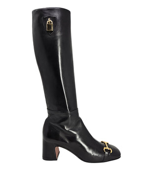 A tall leather boot with a block heel and rounded toe, featuring a metal horsebit-style detail at the front and a small metal padlock accent near the top of the shaft. Designed by Madison in Beverly Hills and handcrafted in Italy