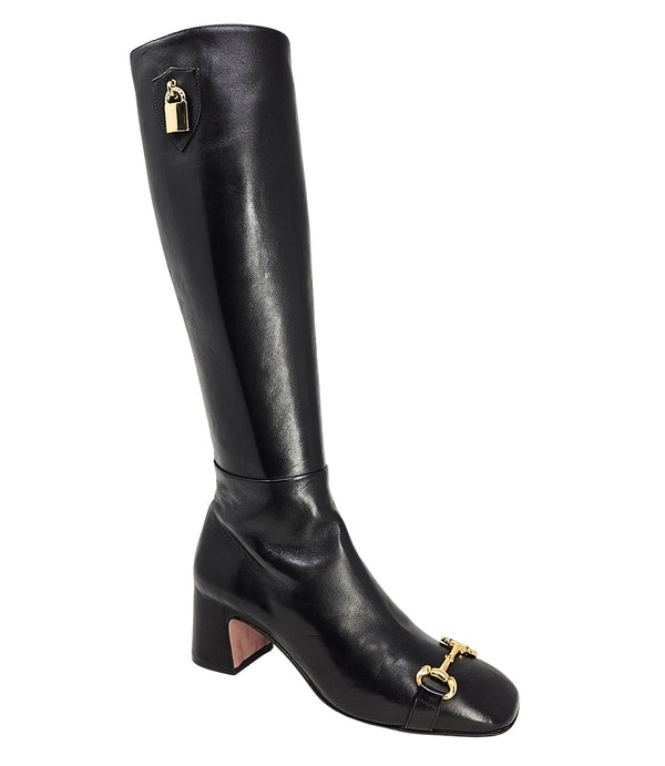 A tall leather boot with a block heel and rounded toe, featuring a metal horsebit-style detail at the front and a small metal padlock accent near the top of the shaft. Designed by Madison in Beverly Hills and handcrafted in Italy