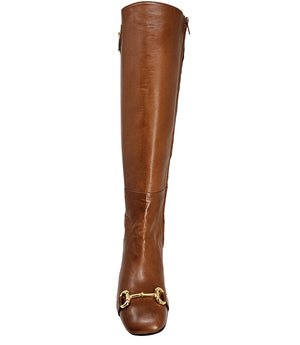 A tall leather boot with a block heel and rounded toe, featuring a metal horsebit-style detail at the front and a small metal padlock accent near the top of the shaft. Designed by Madison in Beverly Hills and handcrafted in Italy