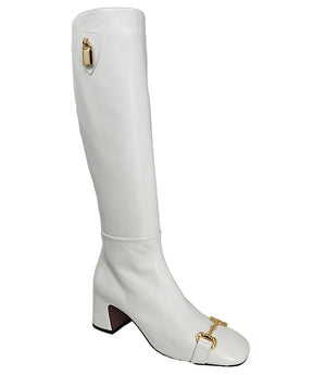 A tall leather boot with a block heel and rounded toe, featuring a metal horsebit-style detail at the front and a small metal padlock accent near the top of the shaft. Designed by Madison in Beverly Hills and handcrafted in Italy