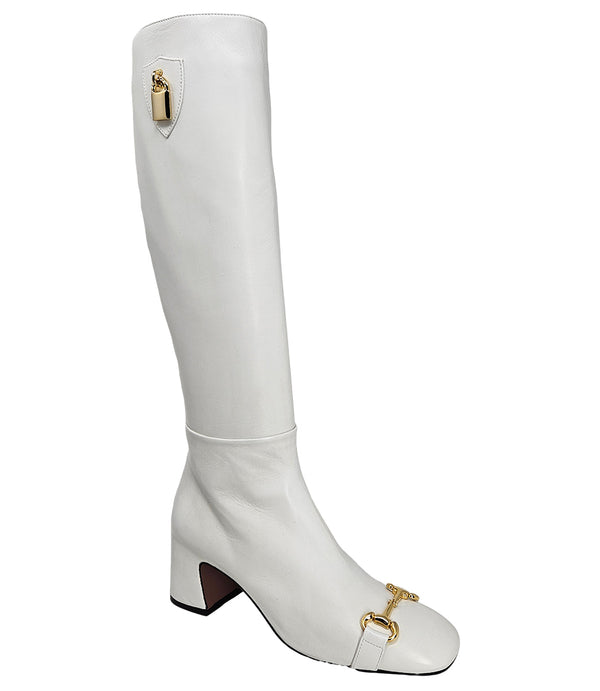 A tall leather boot with a block heel and rounded toe, featuring a metal horsebit-style detail at the front and a small metal padlock accent near the top of the shaft. Designed by Madison in Beverly Hills and handcrafted in Italy