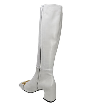 A tall leather boot with a block heel and rounded toe, featuring a metal horsebit-style detail at the front and a small metal padlock accent near the top of the shaft. Designed by Madison in Beverly Hills and handcrafted in Italy
