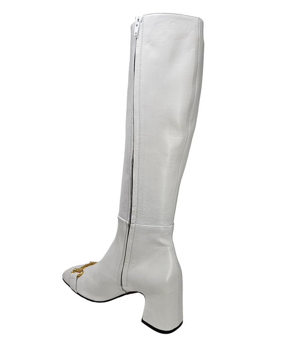 A tall leather boot with a block heel and rounded toe, featuring a metal horsebit-style detail at the front and a small metal padlock accent near the top of the shaft. Designed by Madison in Beverly Hills and handcrafted in Italy