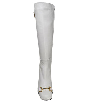 A tall leather boot with a block heel and rounded toe, featuring a metal horsebit-style detail at the front and a small metal padlock accent near the top of the shaft. Designed by Madison in Beverly Hills and handcrafted in Italy