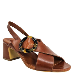 Brown sandal with a large circular buckle on a white background