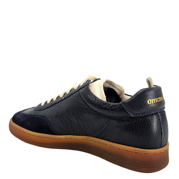 A navy blue leather and suede low-top sneaker with cream laces and a brown rubber sole.