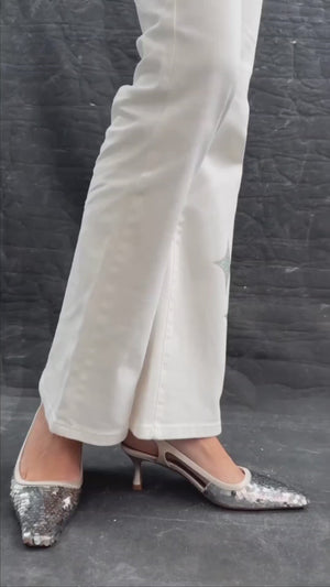 Handcrafted slingback shoe with sequin embellishments, low heel, and pointed toe design. Features an adjustable ankle strap and a textured surface for added visual interest
