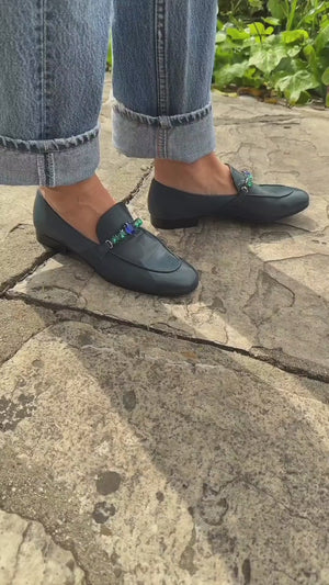 A leather loafer with a low stacked heel and rounded toe, featuring a decorative band adorned with faceted gemstone-style embellishments across the upper. Designed by Madison in Beverly Hills and handcrafted in Italy
