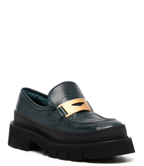 A leather loafer with an exaggerated lug sole and low-cut silhouette, featuring a wide strap with a geometric metal detail across the upper. Designed by Madison in Beverly Hills and handcrafted in Italy.