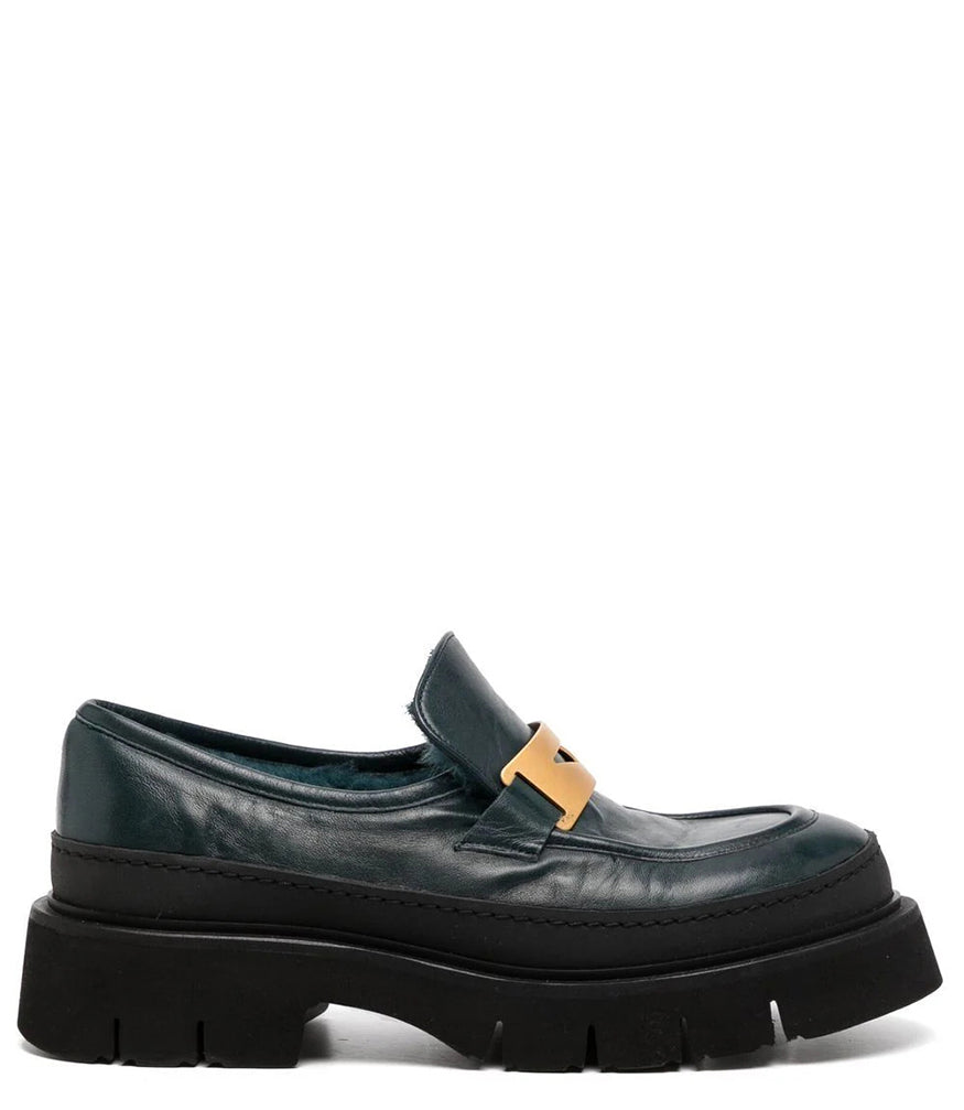 A leather loafer with an exaggerated lug sole and low-cut silhouette, featuring a wide strap with a geometric metal detail across the upper. Designed by Madison in Beverly Hills and handcrafted in Italy.