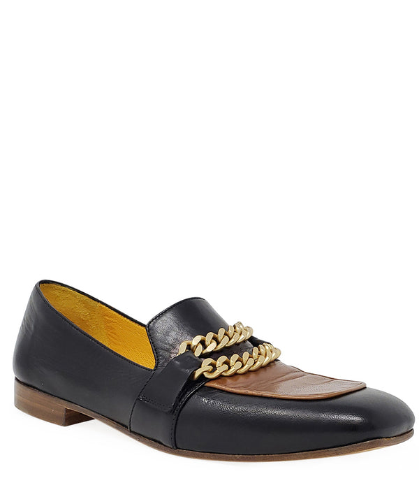 A leather loafer with a flat sole and rounded toe, featuring a contrasting vamp panel and dual chain accents across the upper. Designed by Madison in Beverly Hills and handcrafted in Italy.