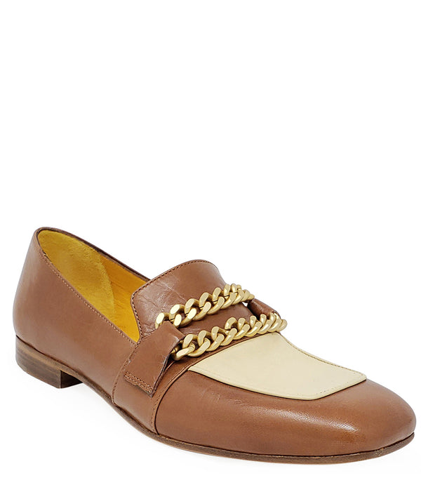 A leather loafer with a flat sole and rounded toe, featuring a contrasting vamp panel and dual chain accents across the upper. Designed by Madison in Beverly Hills and handcrafted in Italy.
