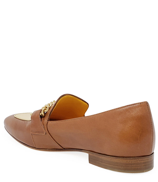 A leather loafer with a flat sole and rounded toe, featuring a contrasting vamp panel and dual chain accents across the upper. Designed by Madison in Beverly Hills and handcrafted in Italy.