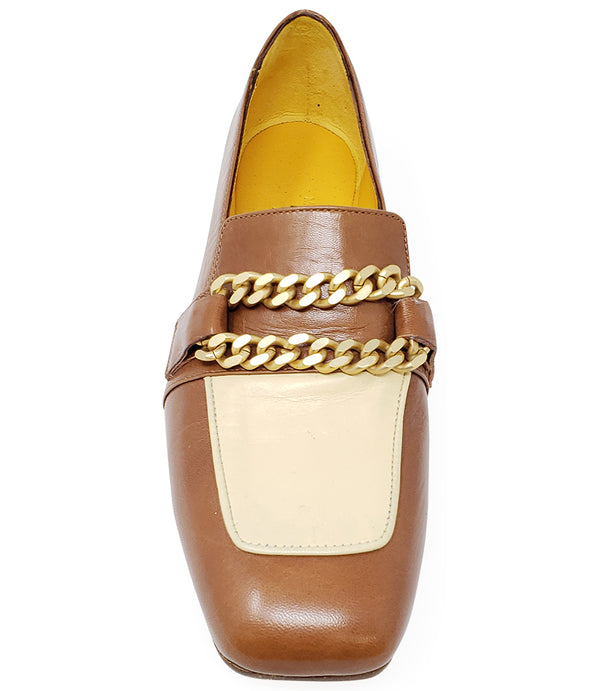 A leather loafer with a flat sole and rounded toe, featuring a contrasting vamp panel and dual chain accents across the upper. Designed by Madison in Beverly Hills and handcrafted in Italy.