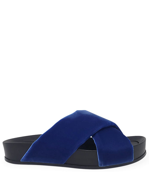 A handcrafted Italian open-toe flat sandal featuring a wide strap with a centered oval gemstone surrounded by circular studs, set on a molded footbed with a low platform sole."