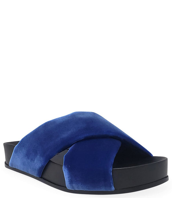 A handcrafted Italian open-toe flat sandal featuring a wide strap with a centered oval gemstone surrounded by circular studs, set on a molded footbed with a low platform sole."