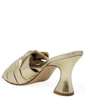 Open-toe mule handcrafted in Italy, featuring a metallic finish, wide vamp with a twisted bow detail, and a flared heel. Shown from multiple angles against a clean background