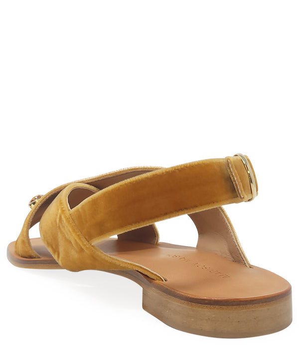 A handcrafted Italian open-toe flat sandal featuring a wide strap with a centered oval gemstone surrounded by circular studs, set on a molded footbed with a low platform sole."