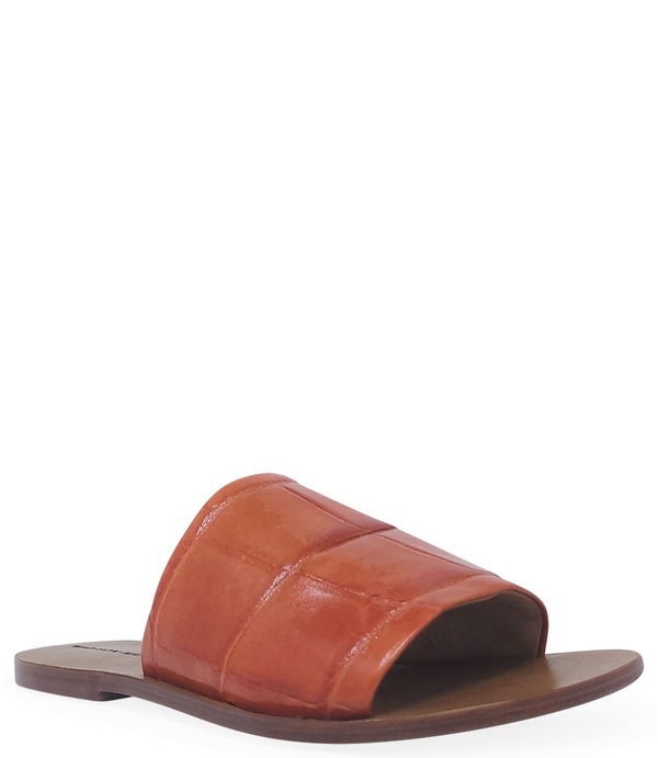 Handmade slide sandal crafted in Italy with a wide, textured band across the foot and a flat leather sole. Features a structured, embossed finish. Displayed from front and side angles against a clean background.