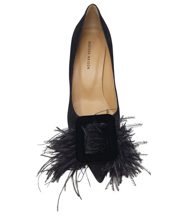 Pointed-toe pump crafted from soft suede with a mid-height stiletto heel, featuring a dramatic feather and velvet buckle embellishment across the toe. Designed with a leather-lined interior and a durable leather outsole for lasting comfort and support. El