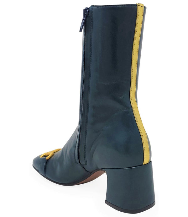 A mid-calf leather boot with a block heel and square toe, featuring a decorative metal accent across the toe. Designed by Madison in Beverly Hills and handcrafted in Italy.