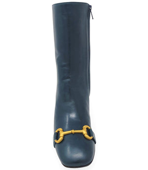 A mid-calf leather boot with a block heel and square toe, featuring a decorative metal accent across the toe. Designed by Madison in Beverly Hills and handcrafted in Italy.