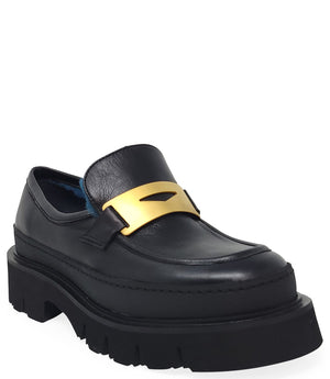 A leather loafer with an exaggerated lug sole and low-cut silhouette, featuring a wide strap with a geometric metal detail across the upper. Designed by Madison in Beverly Hills and handcrafted in Italy.