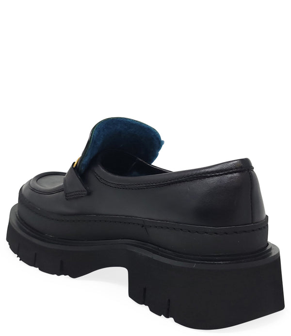 A leather loafer with an exaggerated lug sole and low-cut silhouette, featuring a wide strap with a geometric metal detail across the upper. Designed by Madison in Beverly Hills and handcrafted in Italy.