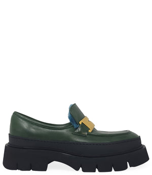 A leather loafer with an exaggerated lug sole and low-cut silhouette, featuring a wide strap with a geometric metal detail across the upper. Designed by Madison in Beverly Hills and handcrafted in Italy.