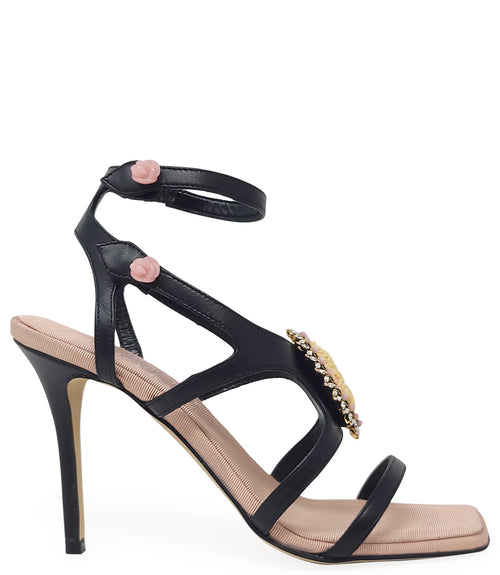 High-heeled sandal made in Italy with an open toe, strappy upper, and sculptural ankle strap secured by floral-shaped accents. Features a raised cameo embellishment with crystal trim on the instep. Presented from multiple angles against a clean background