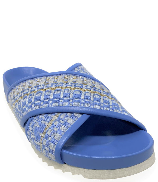A handcrafted Italian open-toe flat sandal featuring a wide strap with a centered oval gemstone surrounded by circular studs, set on a molded footbed with a low platform sole."