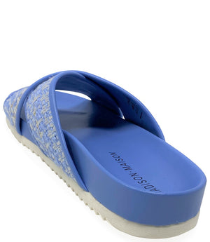 A handcrafted Italian open-toe flat sandal featuring a wide strap with a centered oval gemstone surrounded by circular studs, set on a molded footbed with a low platform sole."