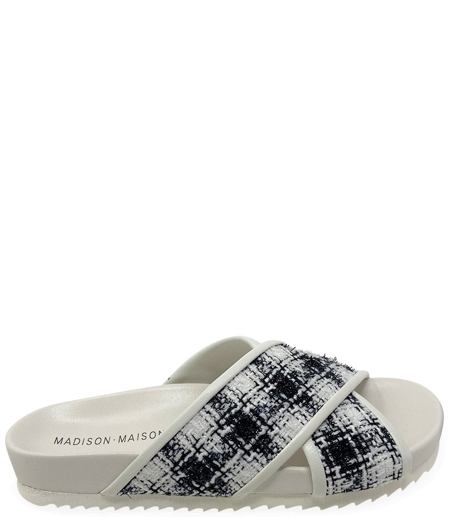 A handcrafted Italian open-toe flat sandal featuring a wide strap with a centered oval gemstone surrounded by circular studs, set on a molded footbed with a low platform sole."