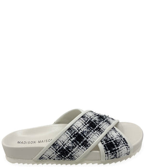 A handcrafted Italian open-toe flat sandal featuring a wide strap with a centered oval gemstone surrounded by circular studs, set on a molded footbed with a low platform sole."