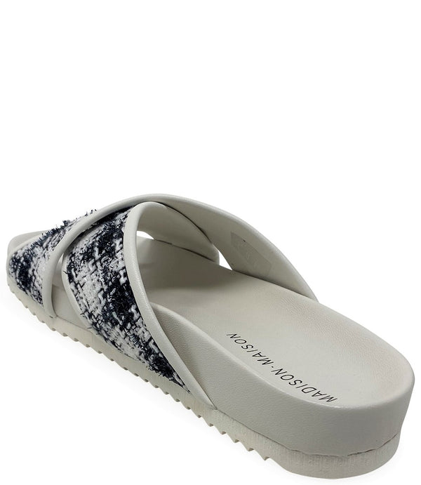 A handcrafted Italian open-toe flat sandal featuring a wide strap with a centered oval gemstone surrounded by circular studs, set on a molded footbed with a low platform sole."