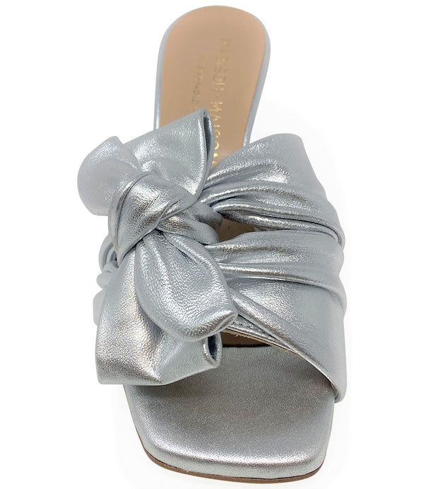 Open-toe mule handcrafted in Italy, featuring a metallic finish, wide vamp with a twisted bow detail, and a flared heel. Shown from multiple angles against a clean background