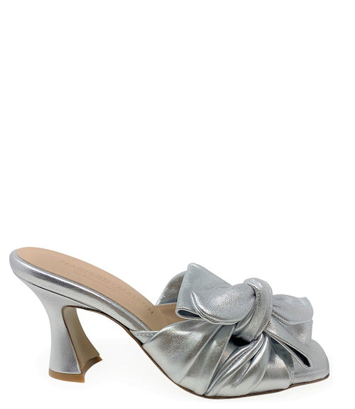 Open-toe mule handcrafted in Italy, featuring a metallic finish, wide vamp with a twisted bow detail, and a flared heel. Shown from multiple angles against a clean background